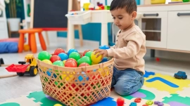 adorable-hispanic-toddler-playing-with-balls-twinnienursery.webp