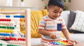 Adorable hispanic toddler playing xylophone standing at home