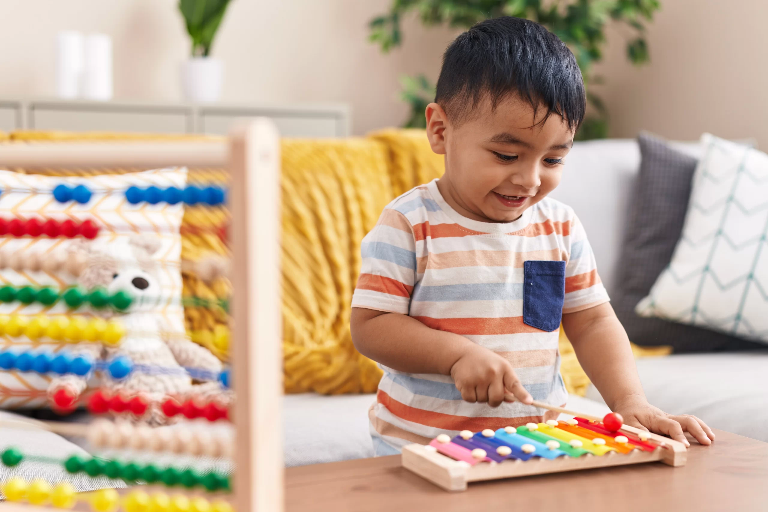 Adorable hispanic toddler playing xylophone standing at home