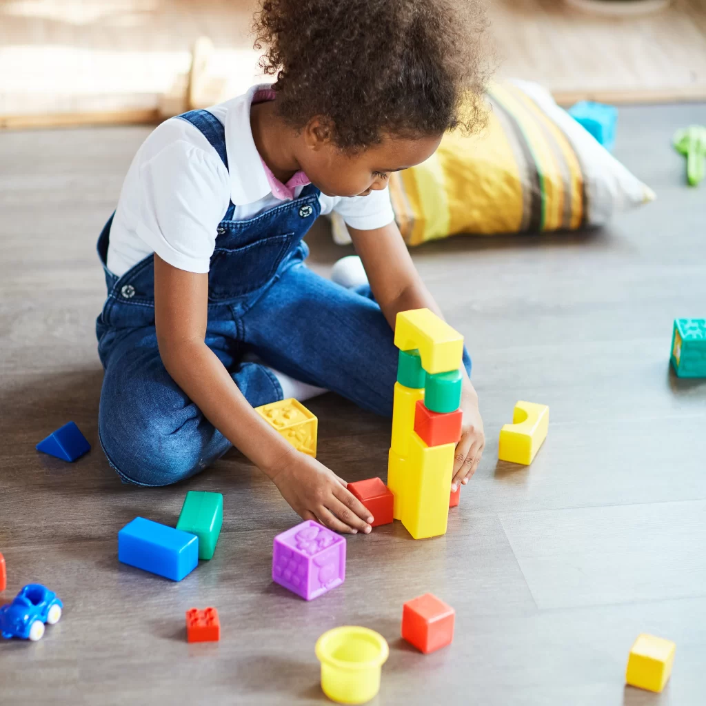 Cute child playing with toy blocks at home